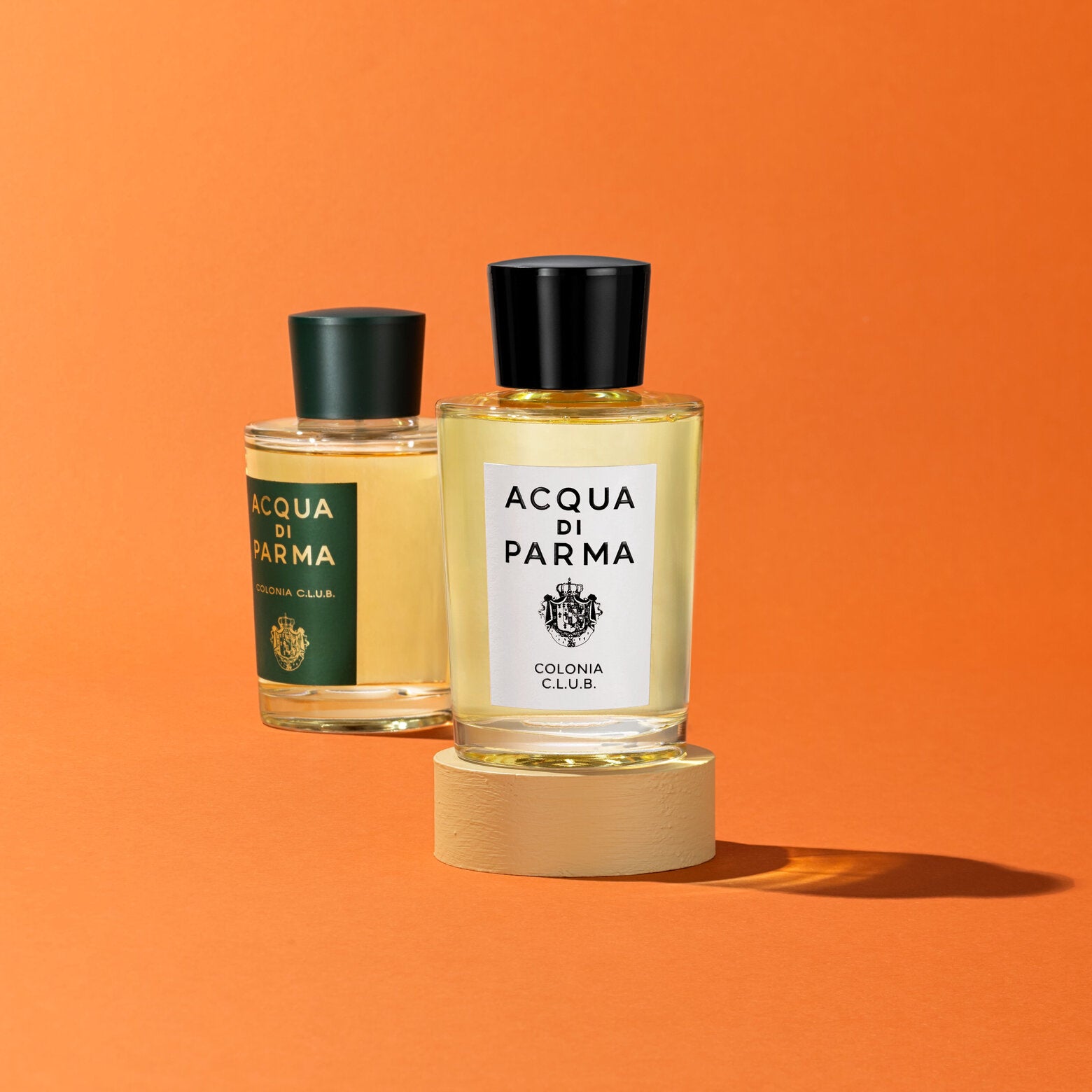 Acqua di Parma Colonia Club EDC bottles displayed on a pedestal against an orange background