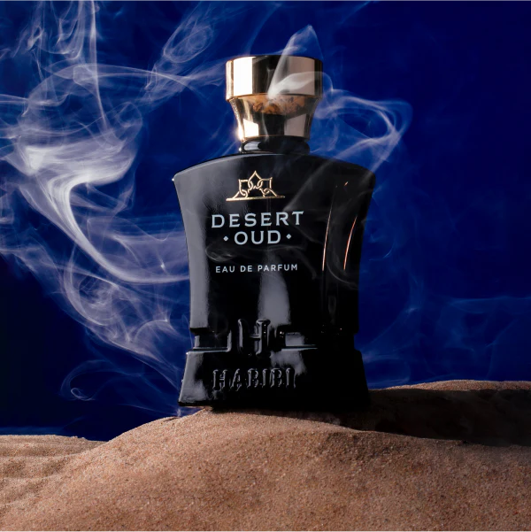 HABIBI NEW YORK Desert Oud perfume black bottle with gold cap on sand with smoky dark blue background