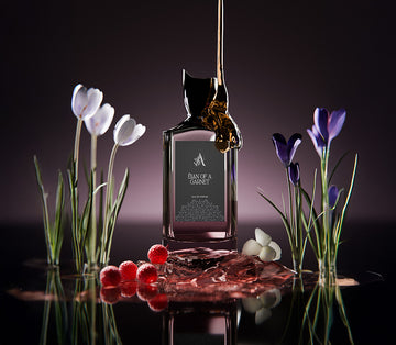 Artal Perfumes Elan of a Garnet perfume bottle with floral and berry accents on reflective surface