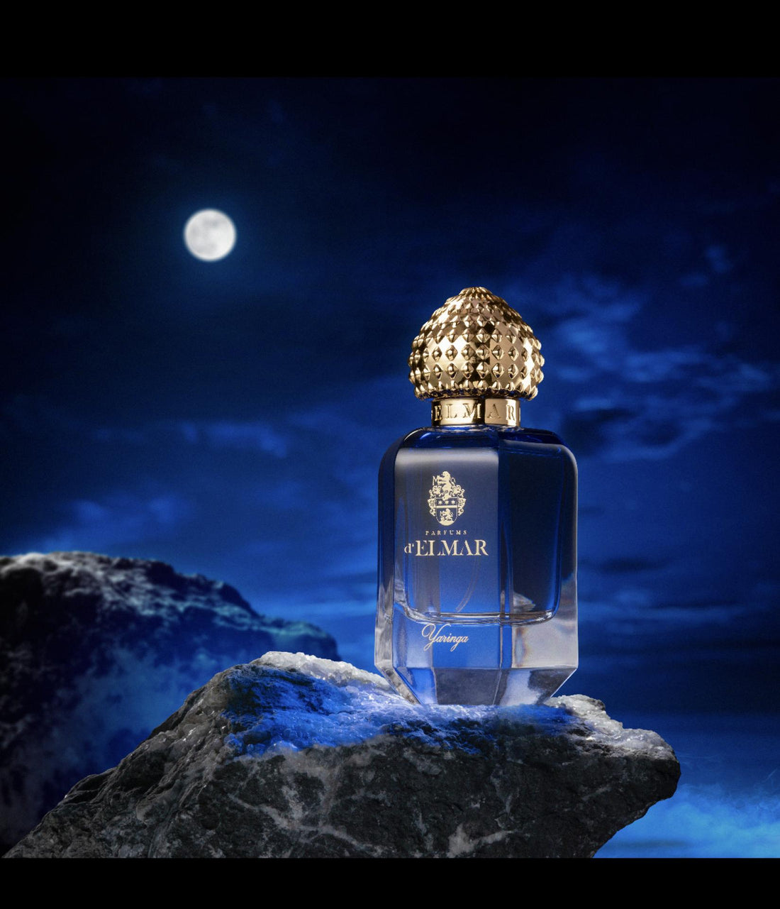 DELMAR YARINGA niche perfume bottle with gold cap on rocky surface under full moon night