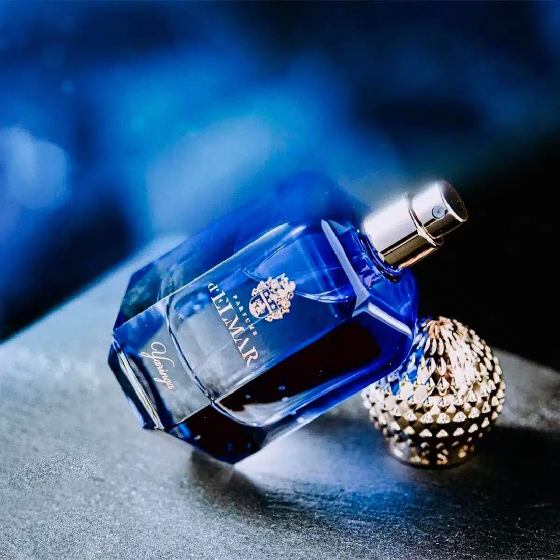 DELMAR YARINGA niche perfume bottle with gold cap on rocky surface under full moon night