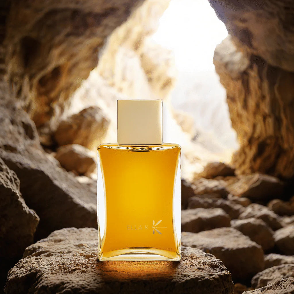 ELLA K Harmattan eau de parfum 100ml bottle with golden liquid placed on rocky surface inside a cave