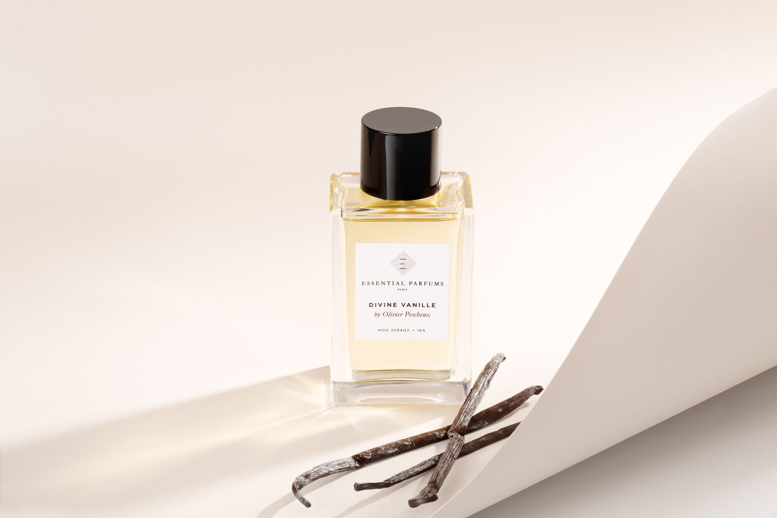 Essential Parfums Divine Vanille eau de parfum bottle with vanilla pods on white background