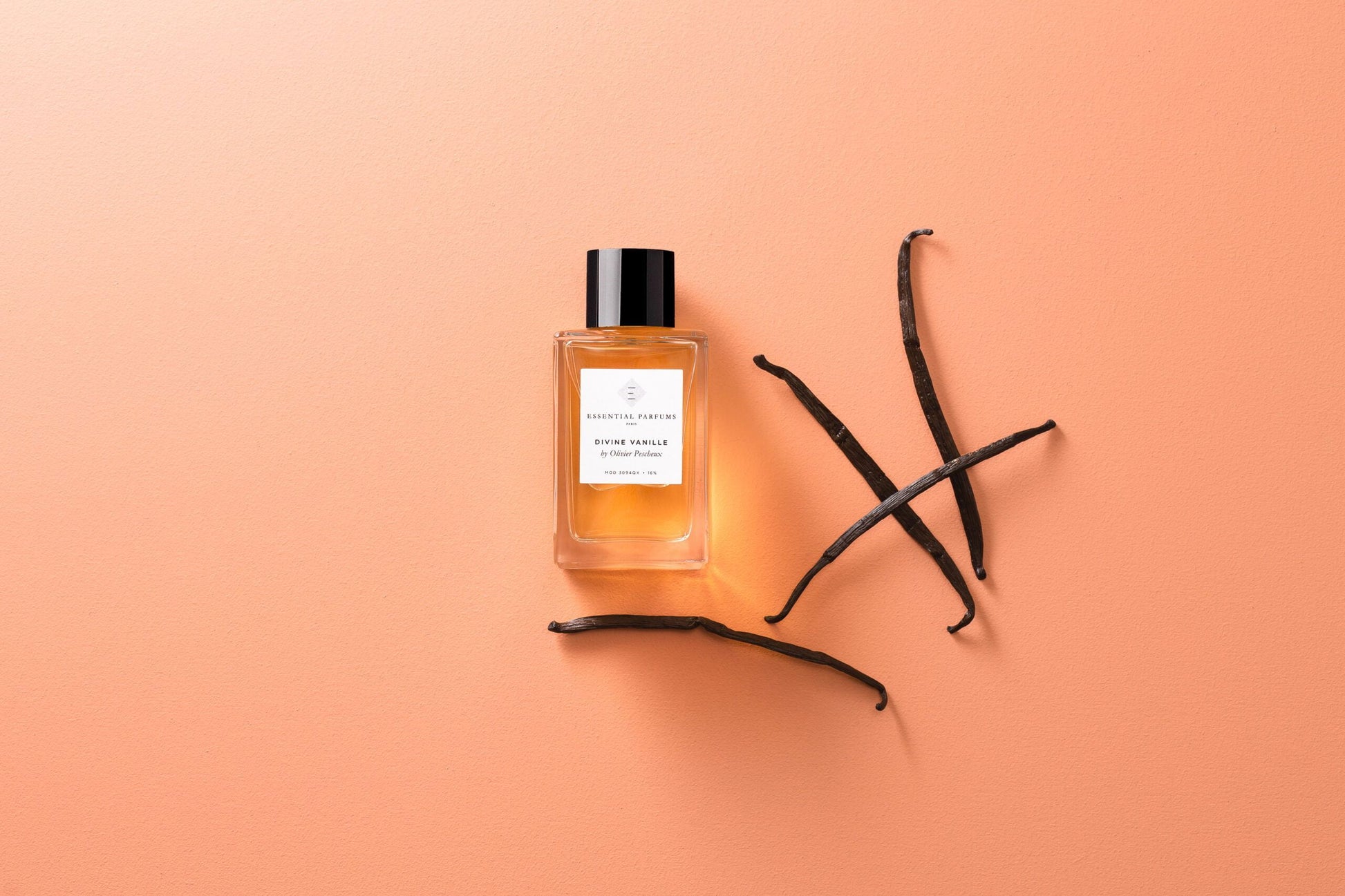 Essential Parfums Divine Vanille eau de parfum bottle with vanilla pods on a peach background