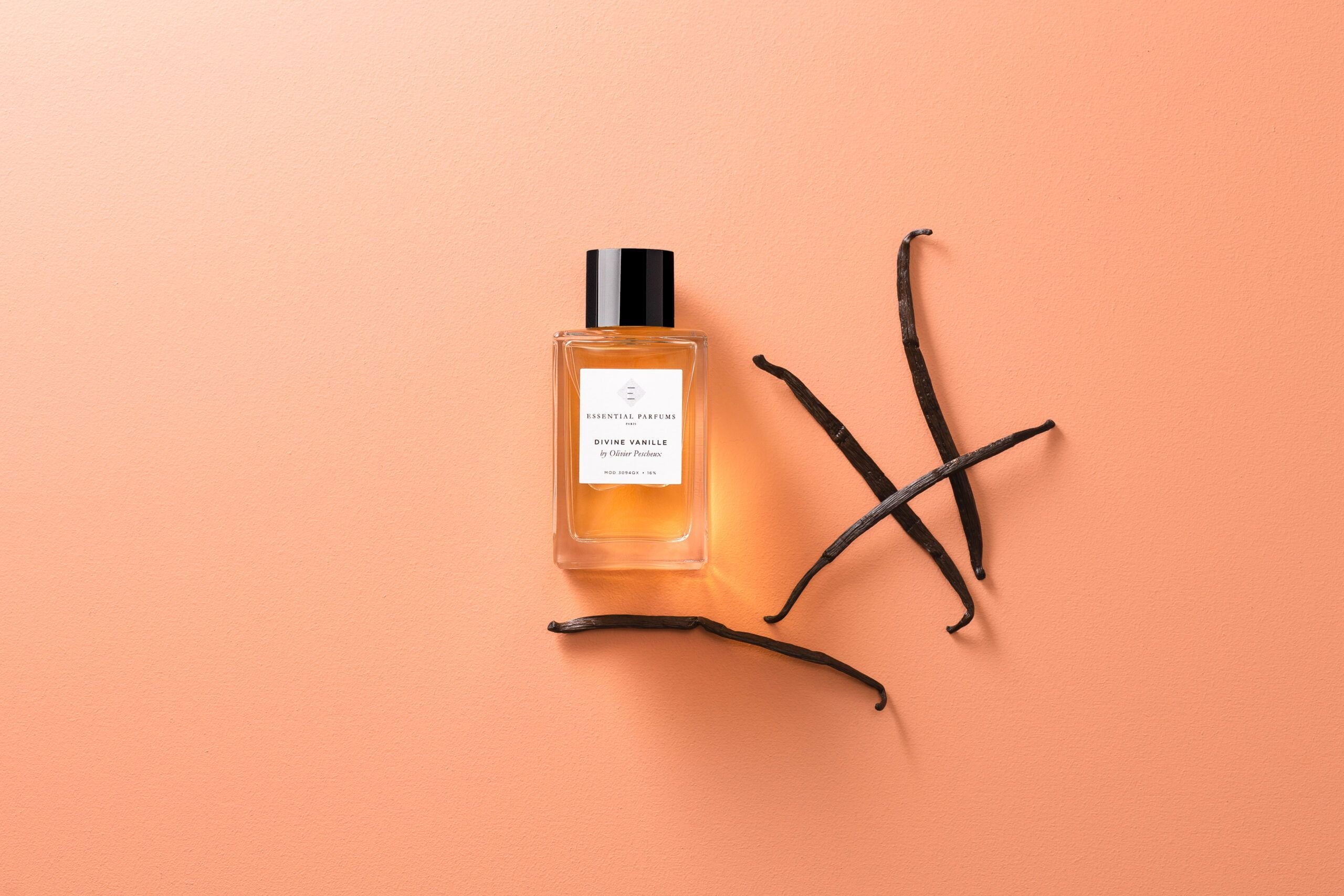 Essential Parfums Divine Vanille eau de parfum bottle with vanilla pods on a peach background