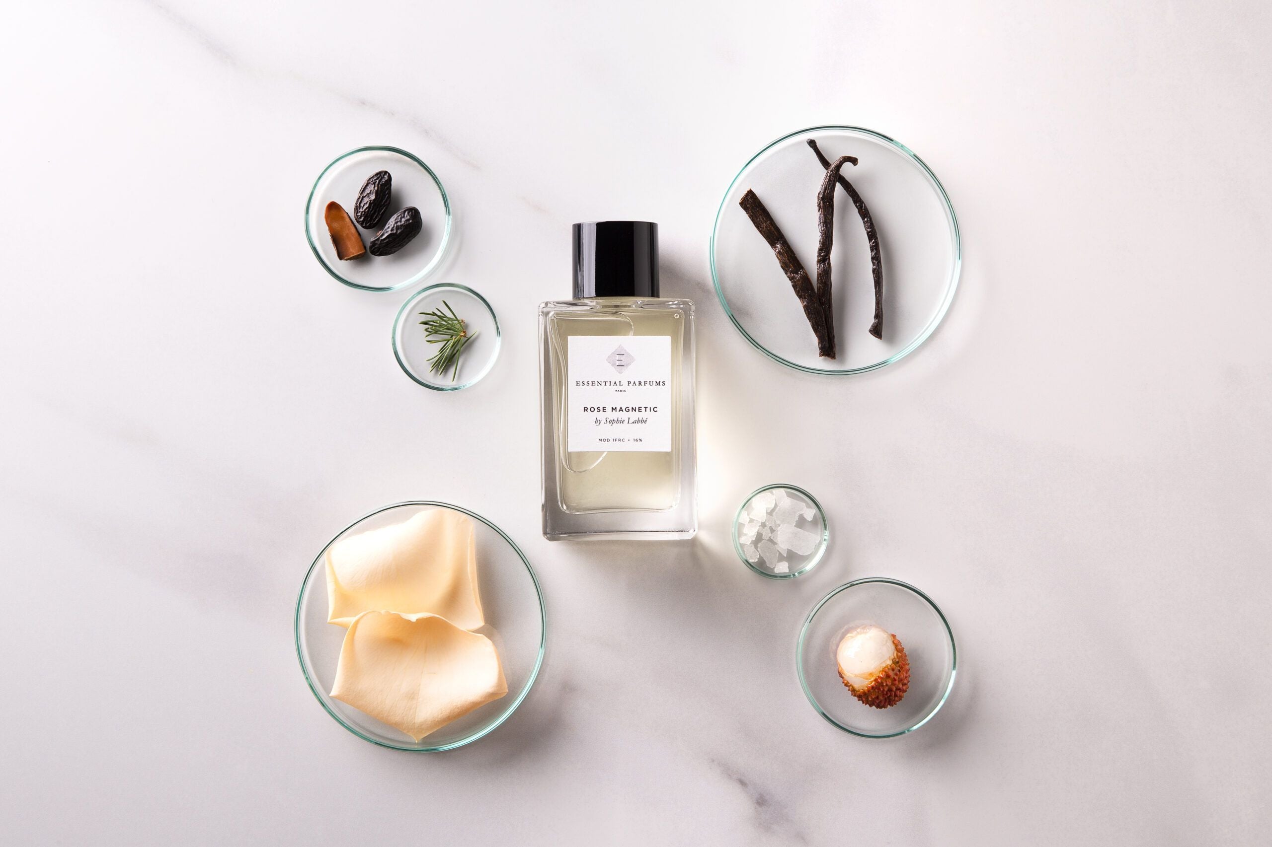 Essential Parfums Rose Magnetic perfume bottle with natural ingredients displayed in glass bowls on marble surface