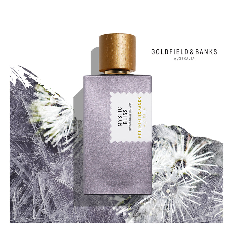 Goldfield & Banks Mystic Bliss perfume 100ml in a purple bottle with wooden cap on floral background