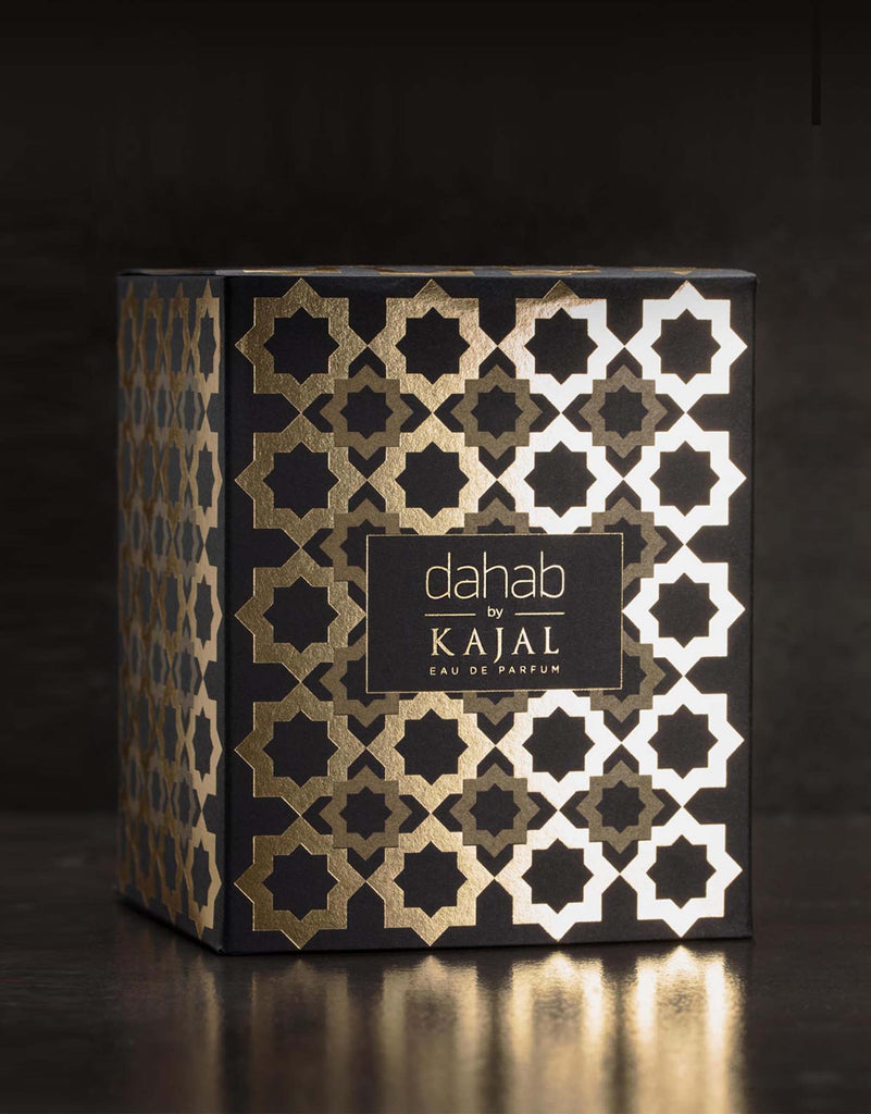 Dahab by Kajal perfume bottle with golden cap and amber liquid inside on a reflective surface