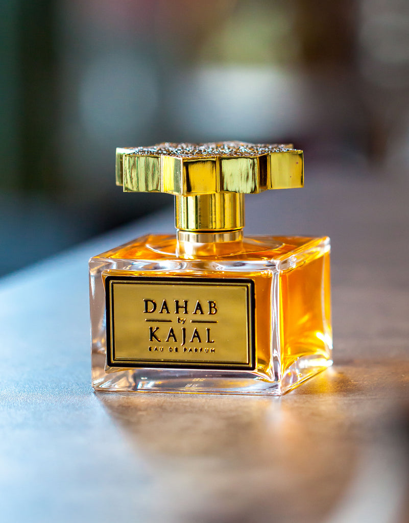 Dahab by Kajal perfume bottle with golden cap and amber liquid inside on a reflective surface