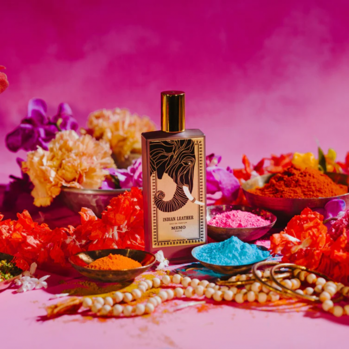 Memo Indian Leather Eau de Parfum bottle set against vibrant flowers and colorful powders