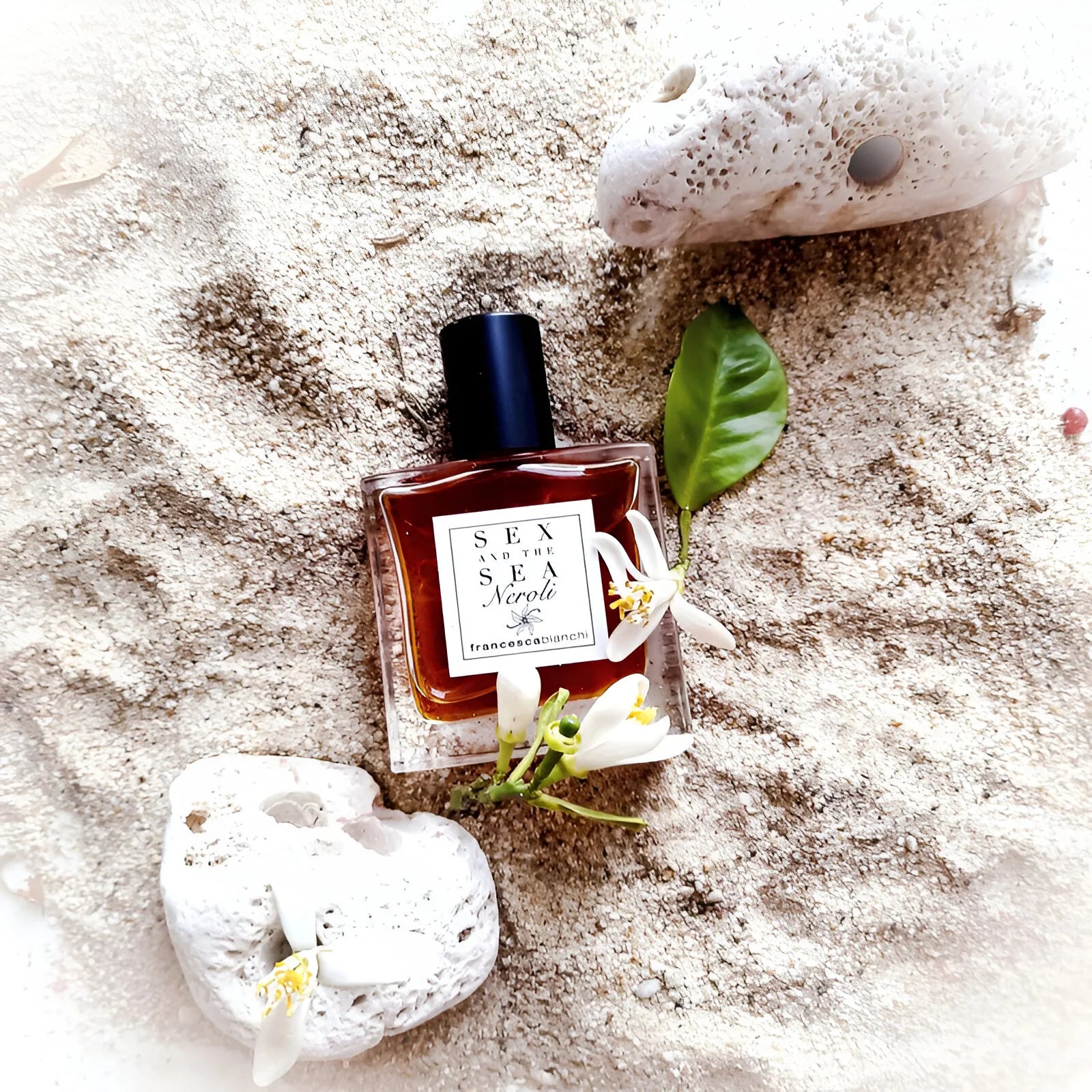 Francesca Bianchi Sex and the Sea Extrait de Parfum bottle on sandy beach with coral and flowers