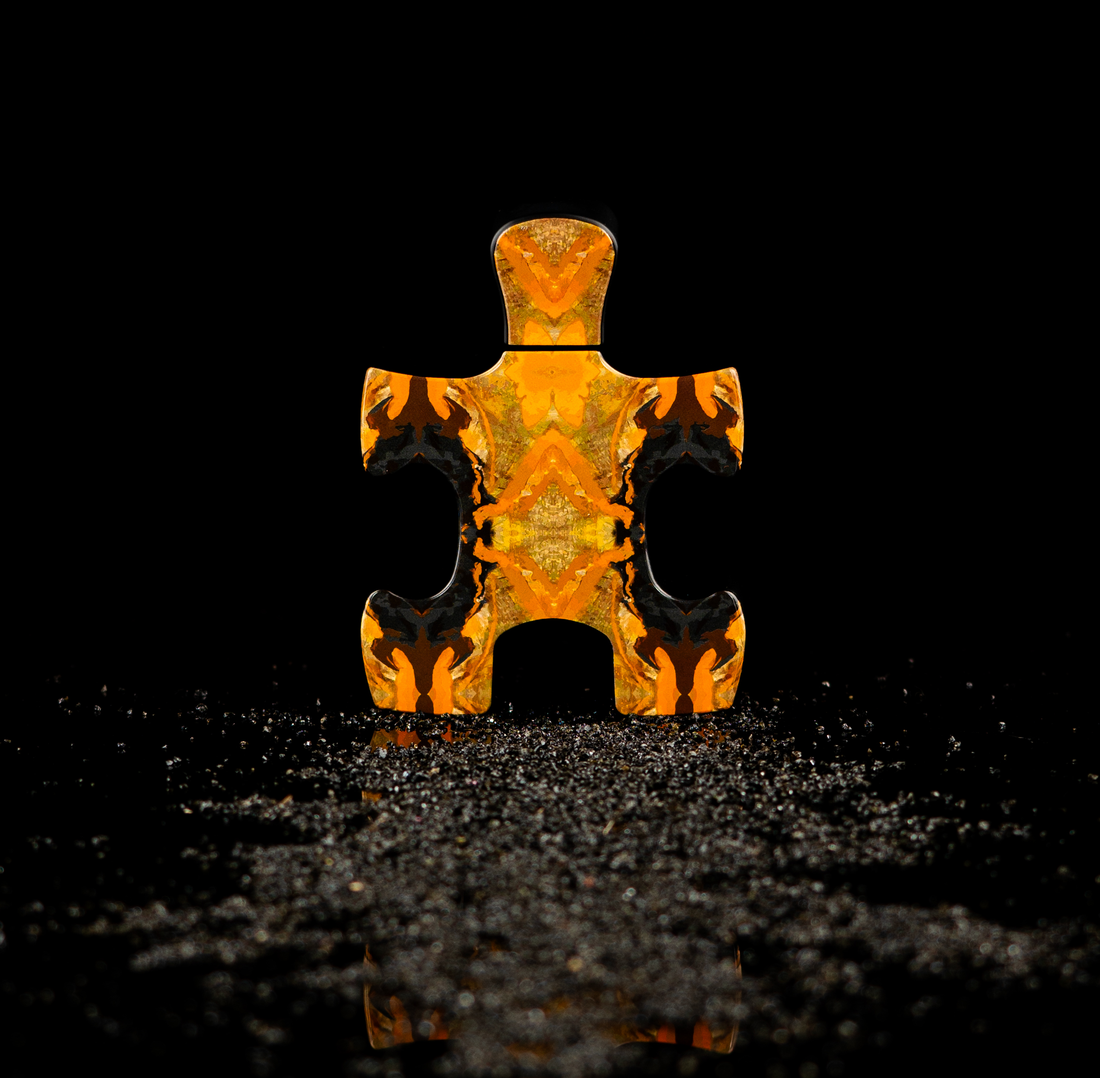 Orange patterned puzzle piece representing Puzzle Daylight perfume by Puzzle Perfume on a reflective black surface