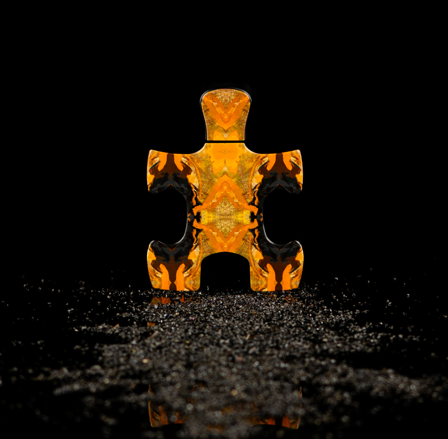 Orange patterned puzzle piece representing Puzzle Daylight perfume by Puzzle Perfume on a reflective black surface