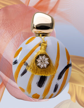 Soul of Mine Twirl niche perfume bottle with gold cap and tassel on white patterned background