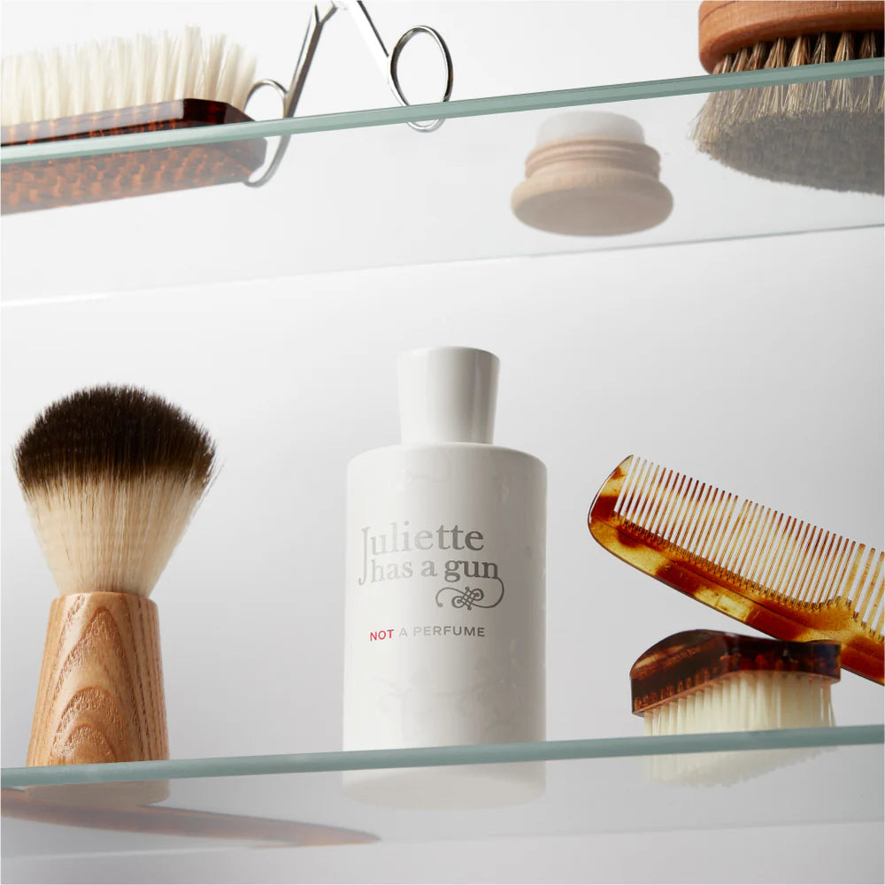 Juliette Has a Gun Not a Perfume 100ml bottle displayed with grooming tools on a glass shelf