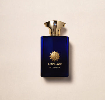 Amouage Interlude Man perfume in a deep blue bottle with a gold cap and emblem