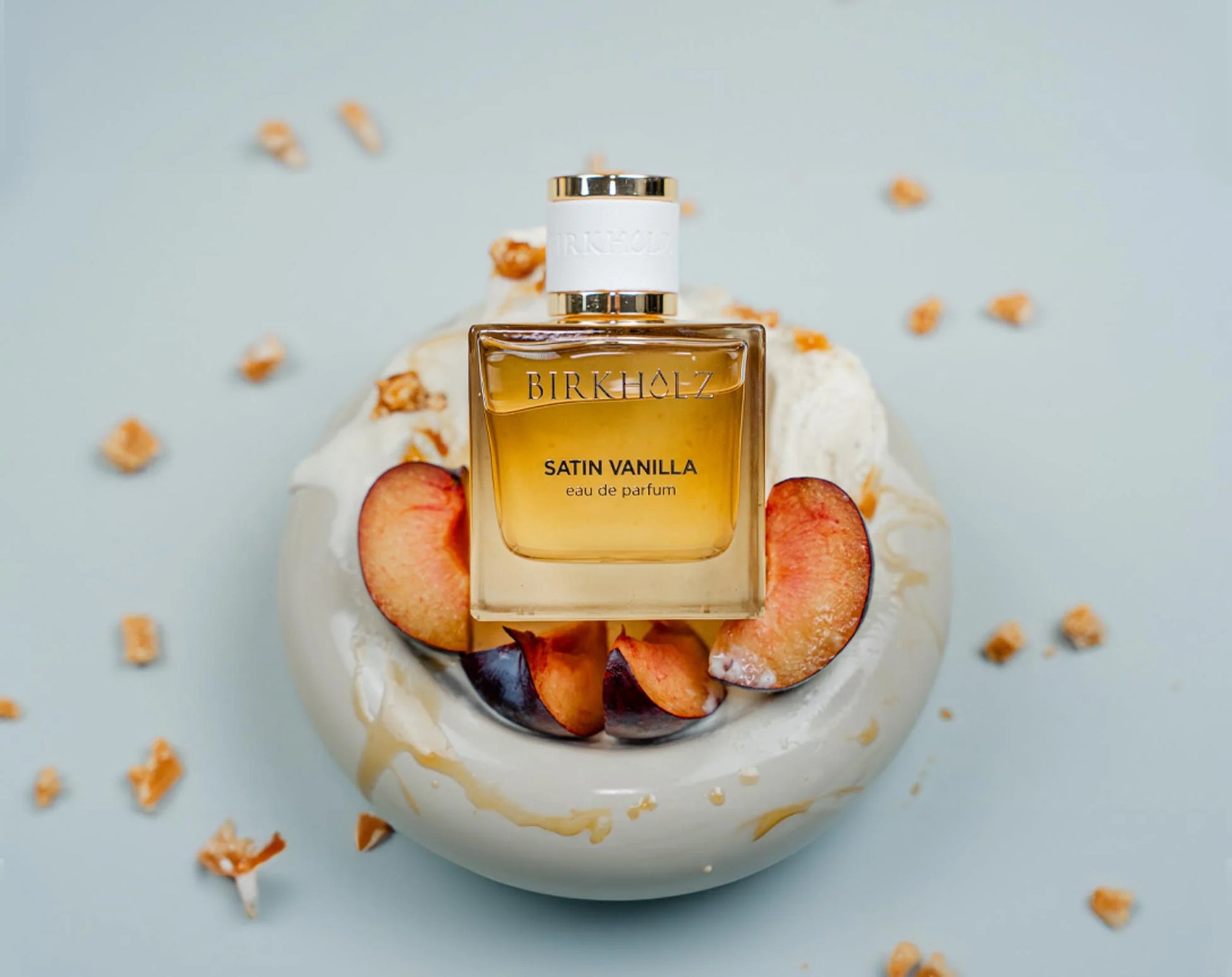 Satin Vanilla Birkholz perfume bottle with peaches and creamy white background for a luxurious scent