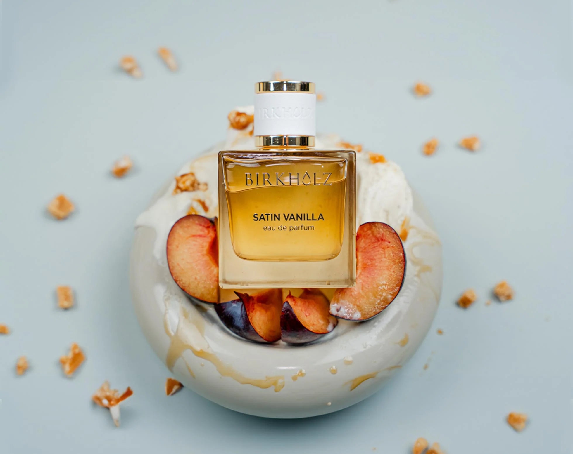 Satin Vanilla Birkholz perfume bottle with peaches and creamy white background for a luxurious scent