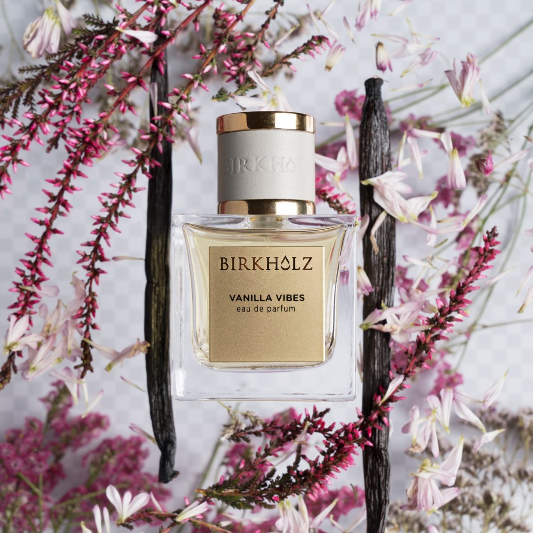 Birkholz Vanilla Vibes eau de parfum bottle surrounded by delicate pink flowers and vanilla pods