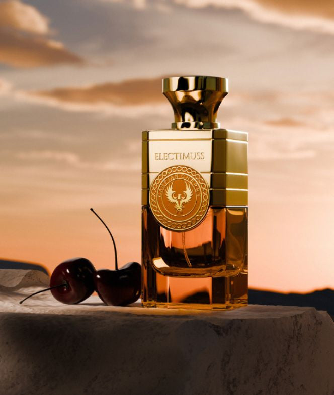 Electimuss Caspian Cherry perfume bottle with gold detailing placed on stone surface with cherry fruits and sunset background