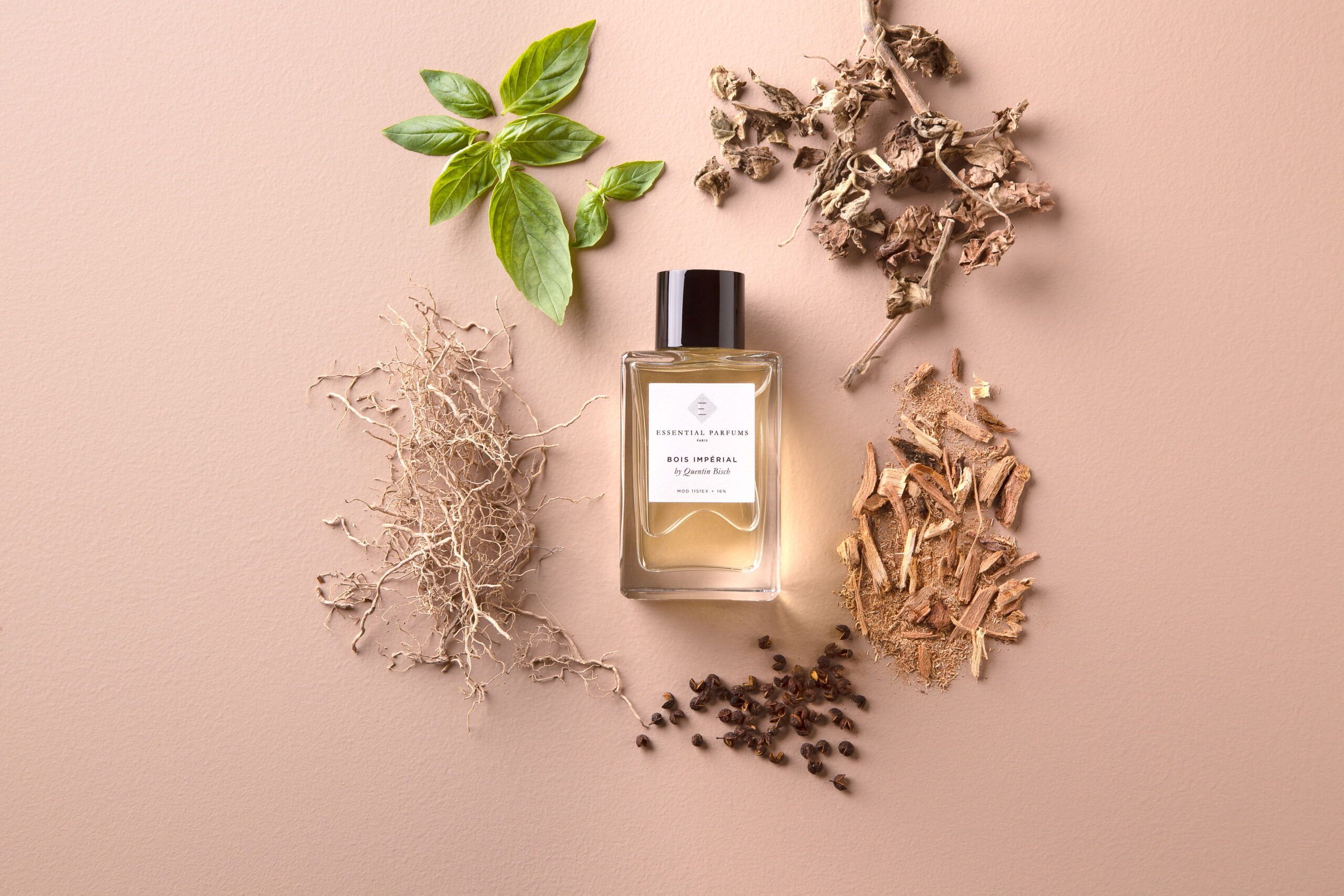 Essential Parfums Bois Imperial Eau de Parfum bottle surrounded by natural ingredients on beige background