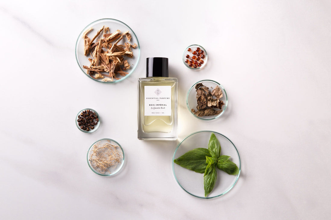 Essential Parfums Bois Imperial Eau de Parfum bottle in white box surrounded by natural wood and herb elements