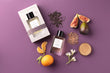 Essential Parfums Fig Infusion perfume bottle and box with fig, orange, flowers, and tea leaves on purple background