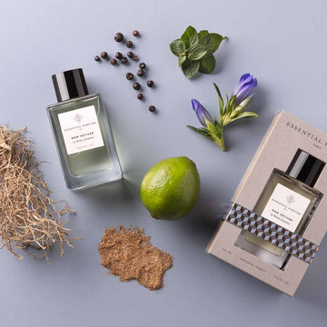 Essential Parfums Mon Vetiver 100ml perfume bottle with packaging and natural ingredients on a gray surface