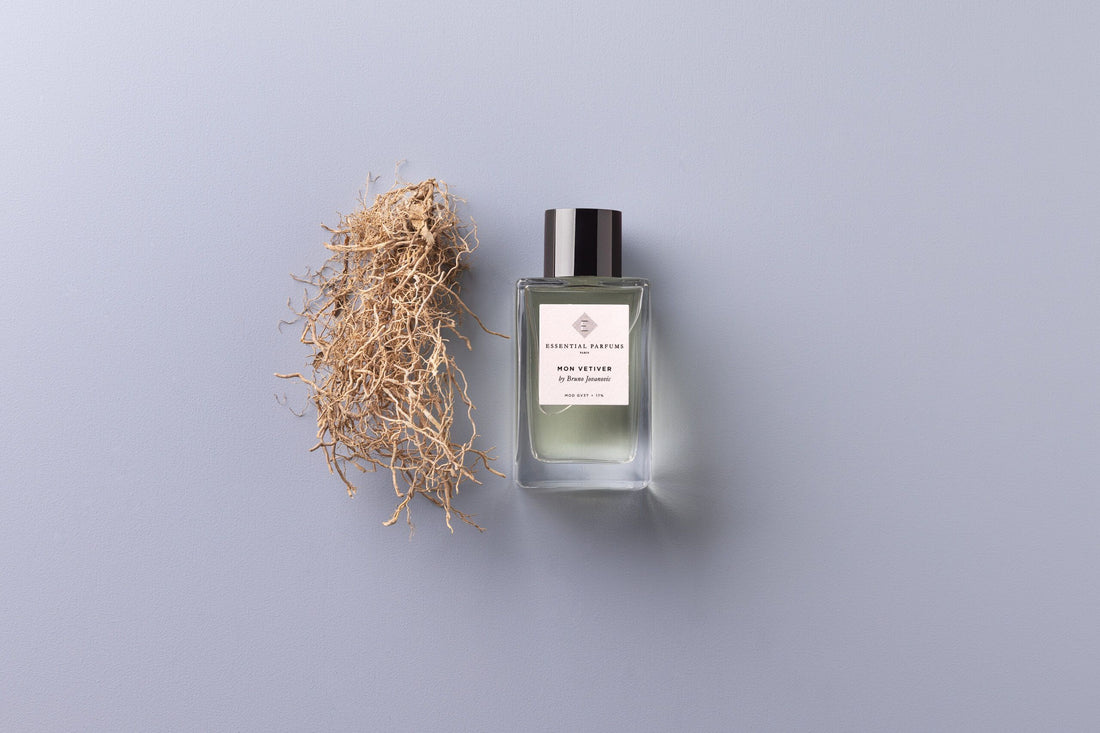 Essential Parfums Mon Vetiver 100ml perfume bottle with packaging and natural ingredients on a gray surface