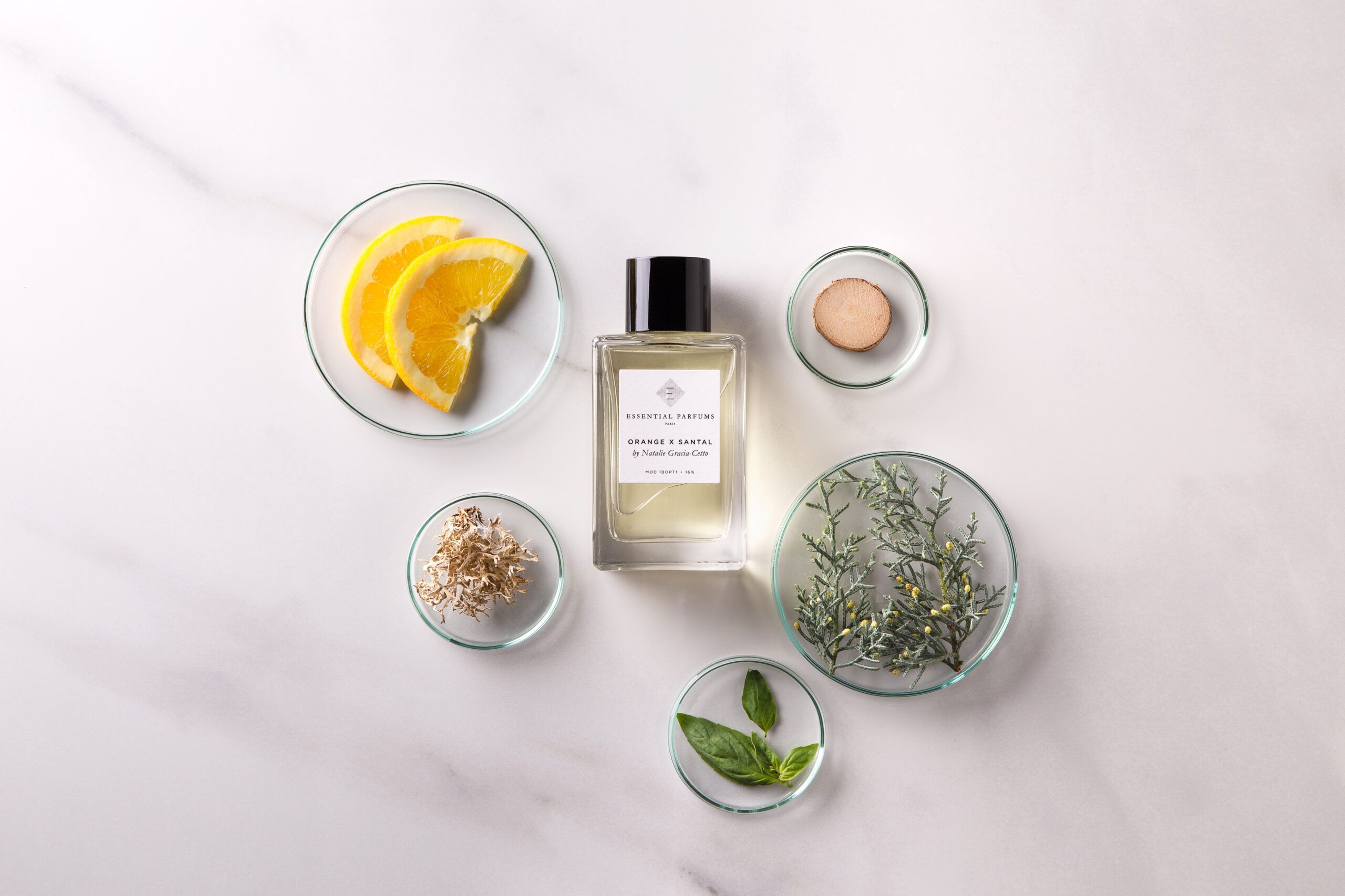 Essential Parfums Orange X Santal 100ml perfume bottle surrounded by orange slices and natural botanical ingredients