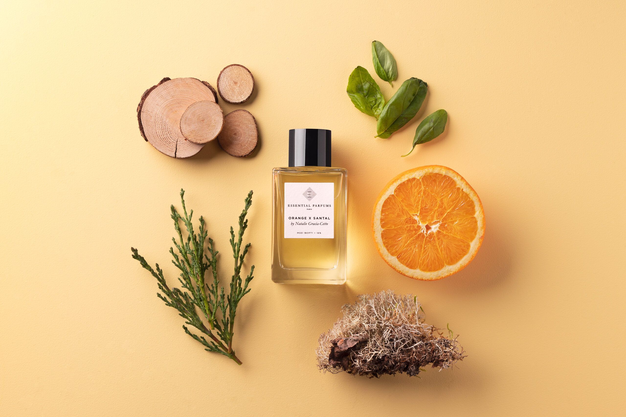 Essential Parfums Orange X Santal 100ml perfume bottle with orange slice and natural wood and greenery
