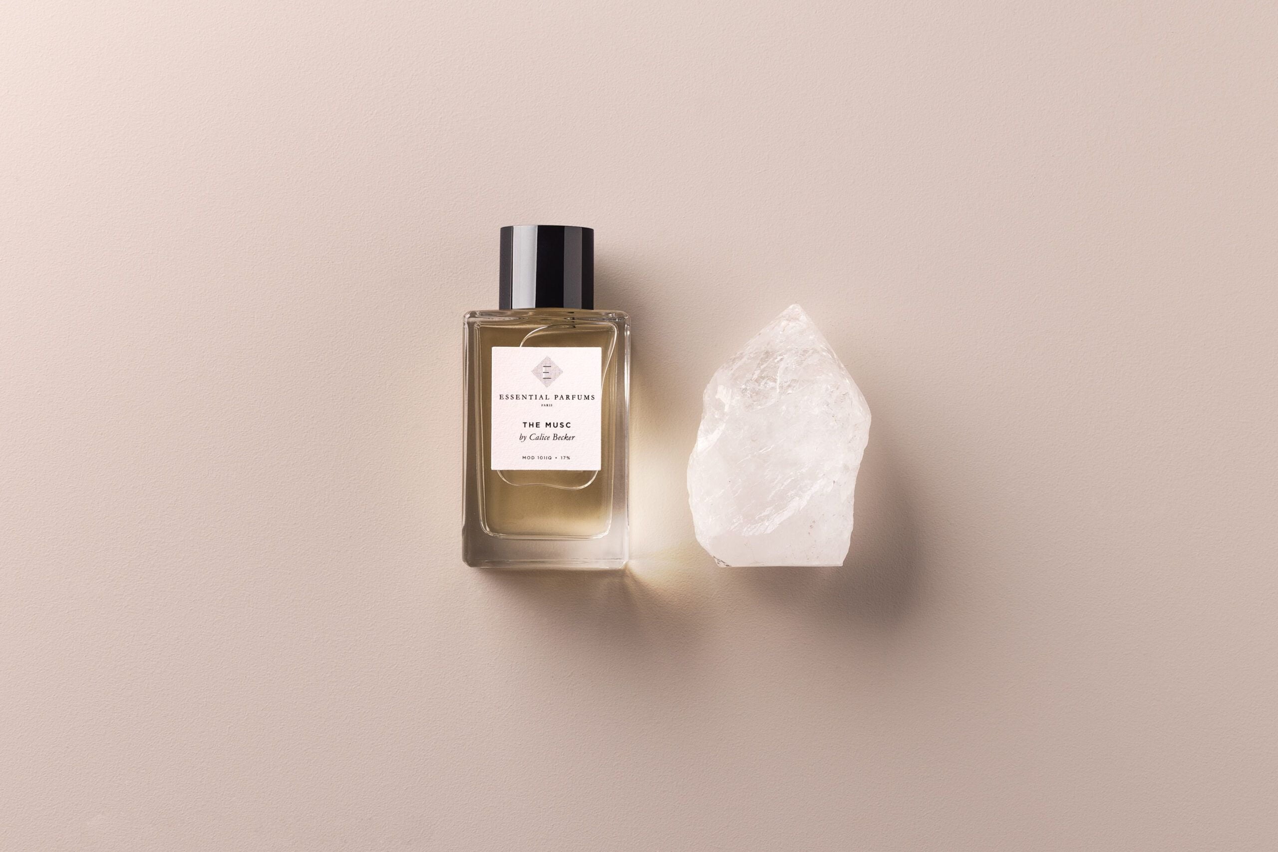 Essential Parfums The Musc 100ml perfume bottle with natural crystal on beige background