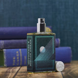 Every Storm A Serenade perfume by Imaginary Authors with dark blue textured bottle and silver cap on wooden surface