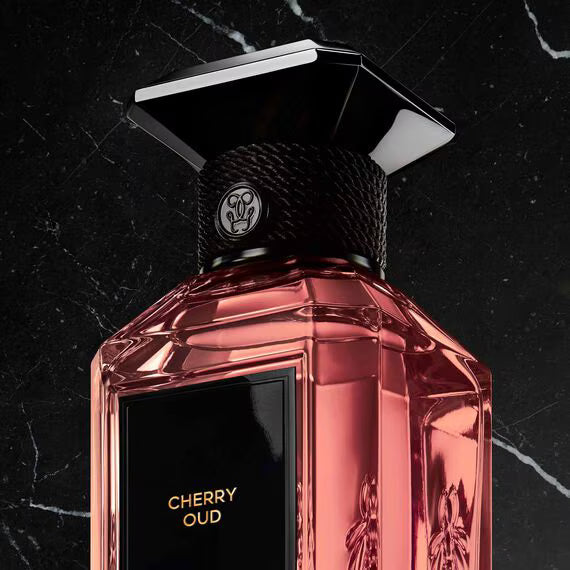 Guerlain Cherry Oud perfume in a stylish bottle with a pink hue on a dark marble background