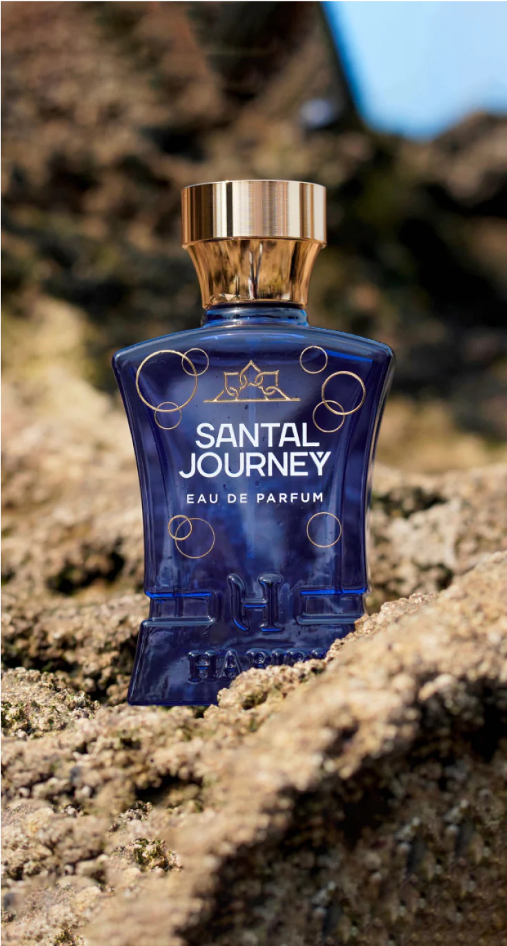 Santal Journey perfume by HABIBI NEW YORK in a blue bottle with gold cap placed on textured rock surface