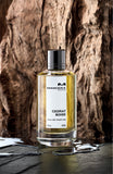 Mancera Cedrat Boise perfume bottle with golden liquid placed against textured wooden background
