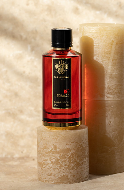 Mancera Red Tobacco perfume Dubai in a red bottle with black and gold label on stone pedestal