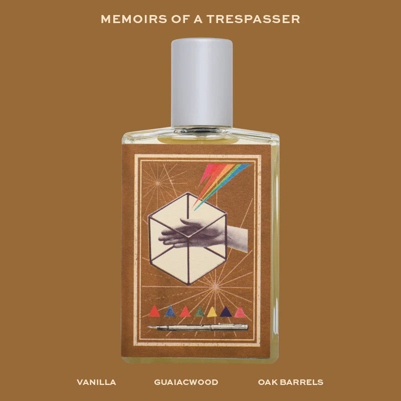 Imaginary Authors MEMOIRS OF A TRESPASSER fragrance bottle with brown label and colorful design on wooden surface