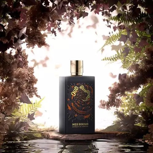 MES BISOUS Oud Hypnotique perfume bottle with gold cap surrounded by mystical forest foliage