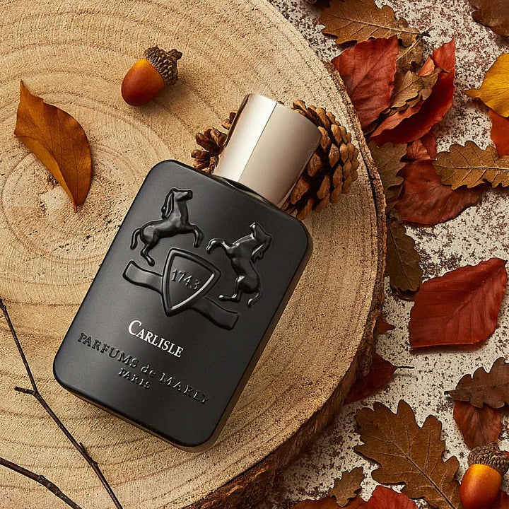 Parfums De Marly Carlisle EDP 125ml black bottle with gold cap on wood slice surrounded by autumn leaves