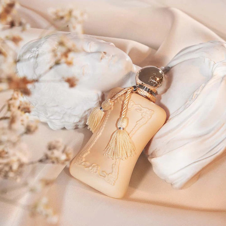 Parfums De Marly Cassili 75ml perfume bottle with gold tassel placed on soft beige fabric near white marble sculpture