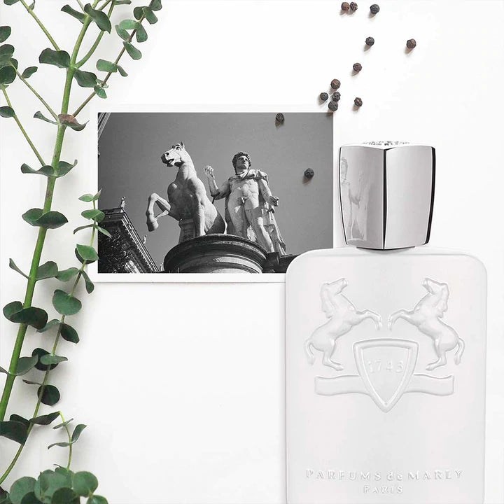 Parfums De Marly Galloway Eau de Parfum white bottle with silver cap surrounded by greenery and black and white statue photo