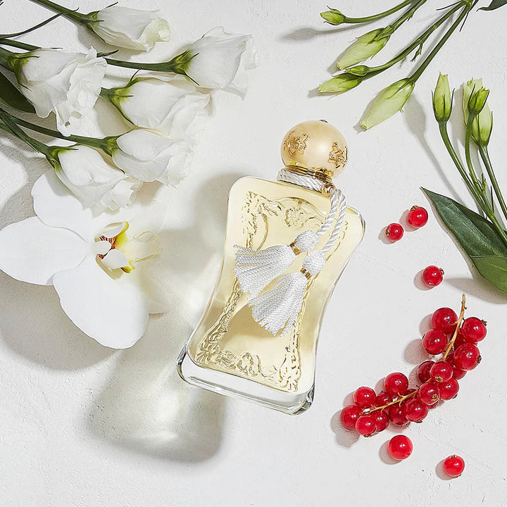 Elegant Parfums De Marly Meliora eau de parfum gold bottle with white tassel surrounded by white flowers and red berries