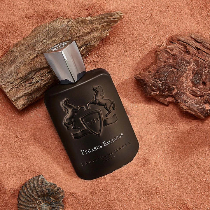 Parfums de Marly Pegasus Exclusif Dubai black perfume bottle on sand with wood and shell accents