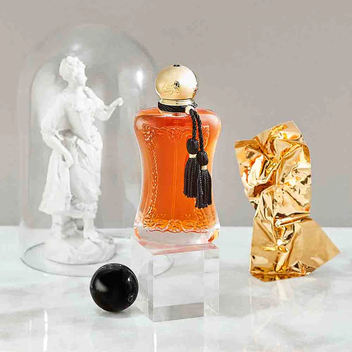 Parfums De Marly Safanad EDP perfume bottle with amber liquid and gold cap displayed on a clear stand