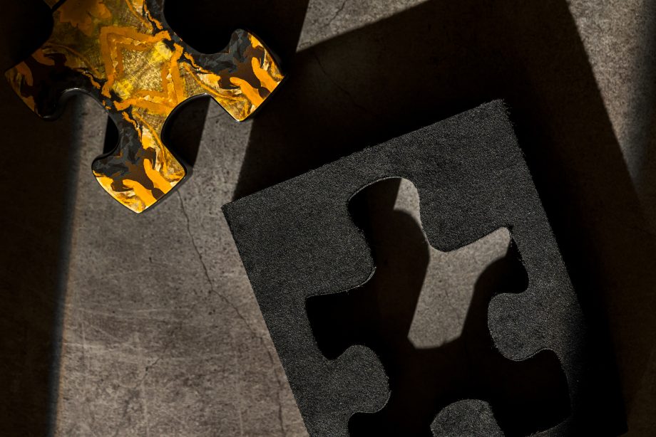 Close-up of Puzzle Daylight perfume puzzle piece design with textured black and gold patterns