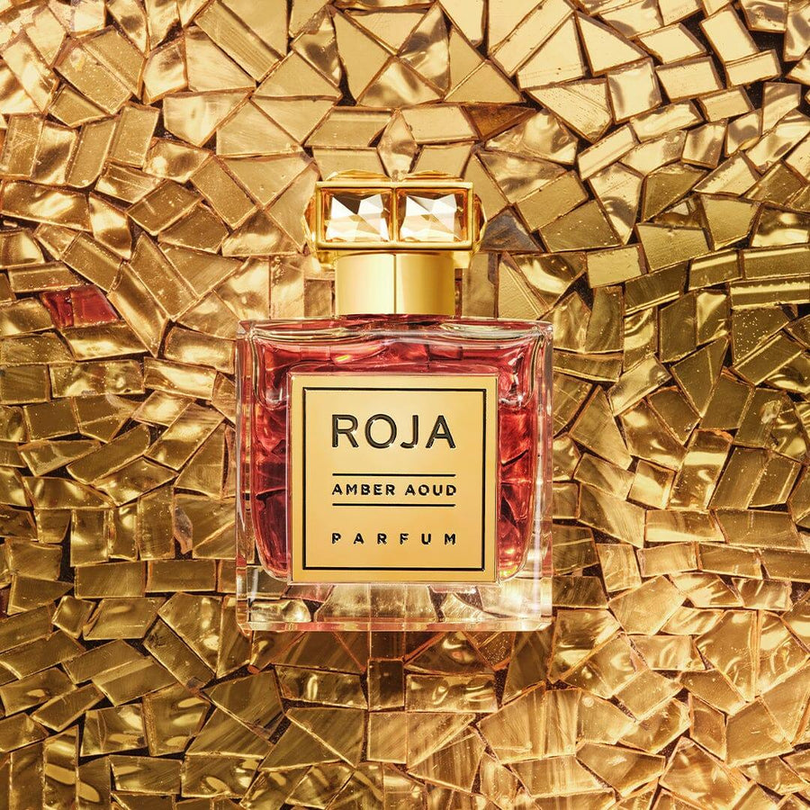 Roja Parfums amber oud parfum for sale in elegant glass bottle with gold label on gold mosaic background