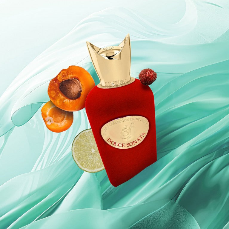 SOSPIRO Sospiro Dolce Sonata 100ml perfume bottle in red velvet with gold cap on wooden surface surrounded by fruit and leaves