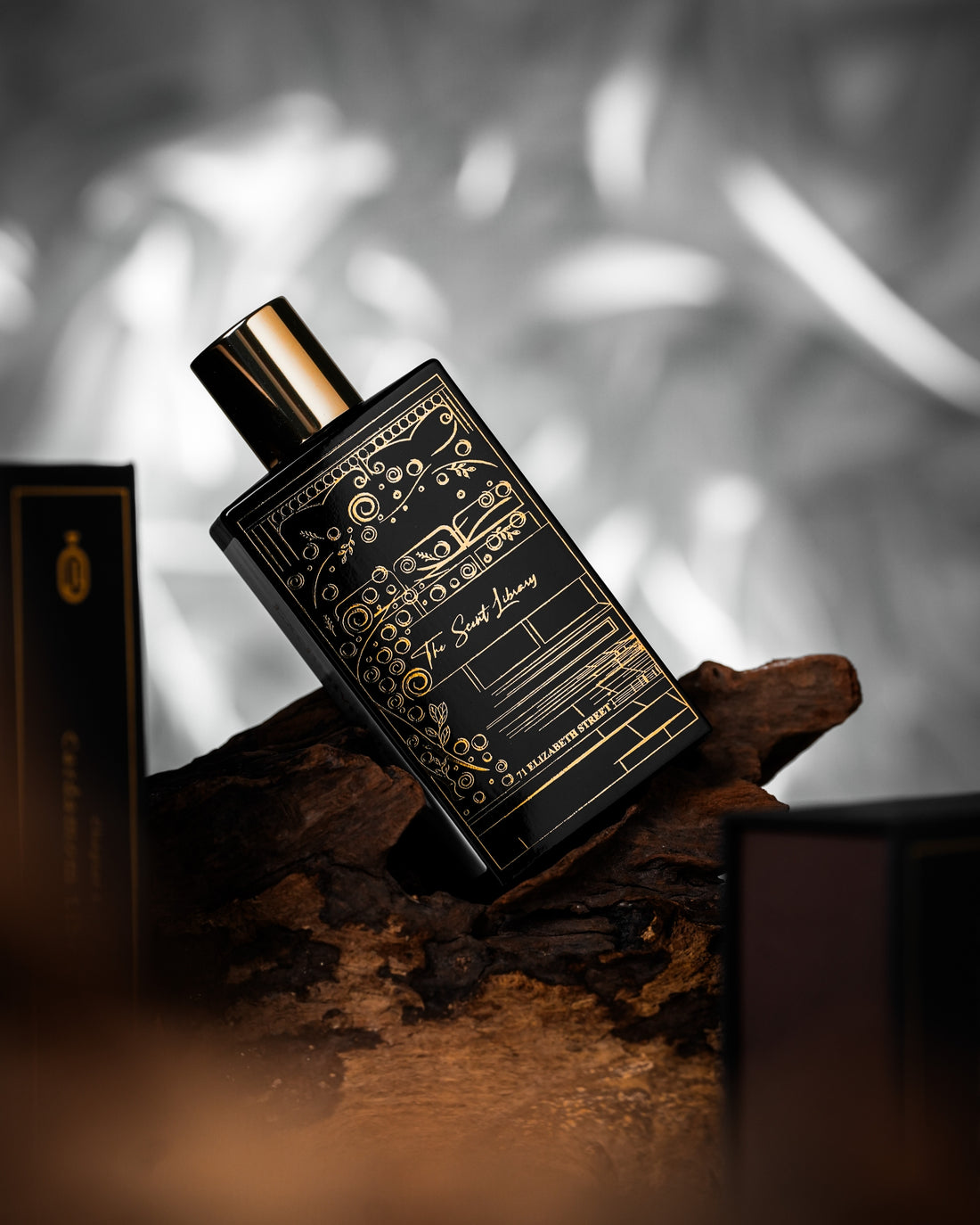 71 Elizabeth Street eau de parfum by The Scent Library, a black bottle with a gold cap and ornate gold line-art of a storefront, Exclusive Chapter side label
