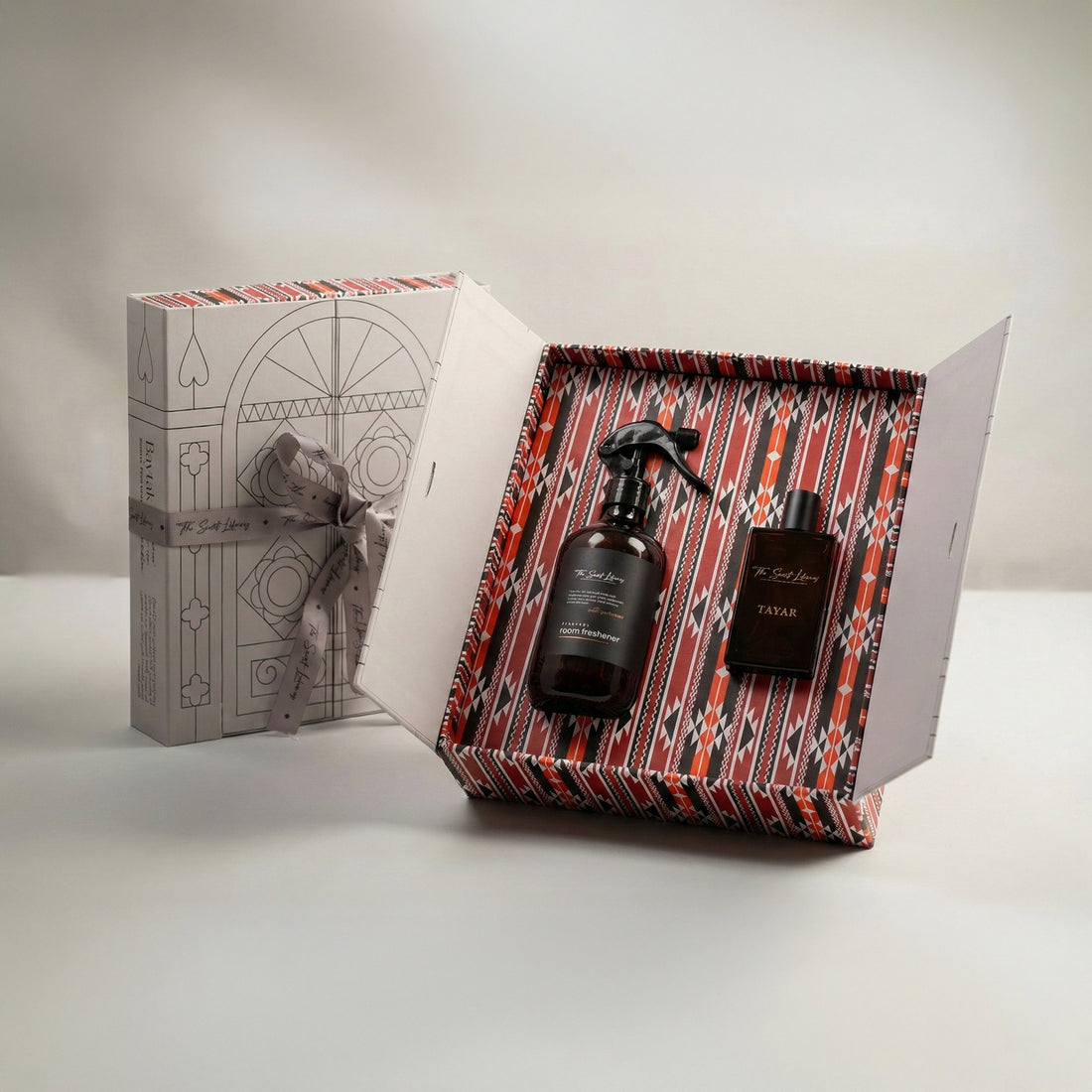 The Elite Set by Baytak, a room freshener and a black Tayar perfume in a red Sadu-patterned gift box beside a white ribboned box, by The Scent Library